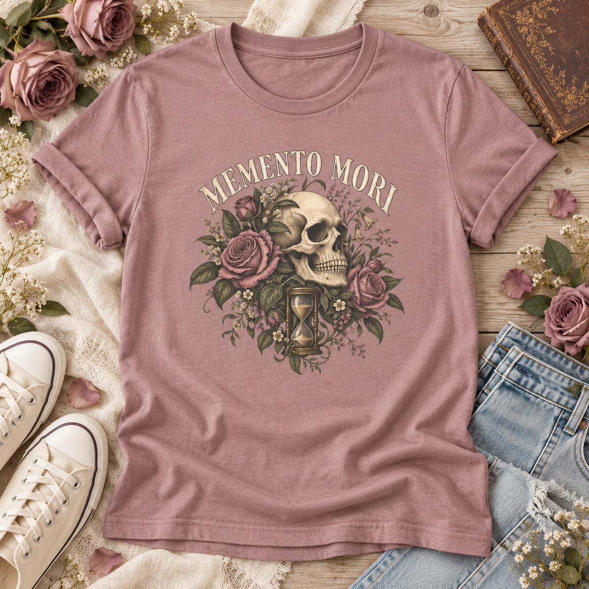 Mauve T-shirt with “Memento Mori” lettering above a vintage skull, mauve roses, leafy details, and an hourglass.