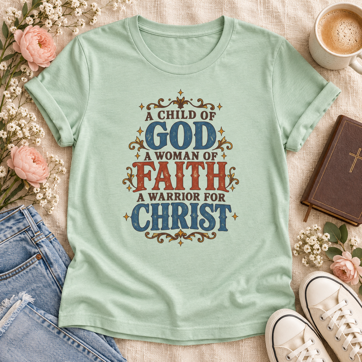 Mint T-shirt reading “A Child of God, A Woman of Faith, A Warrior for Christ,” with blue and rust lettering and golden flourishes.